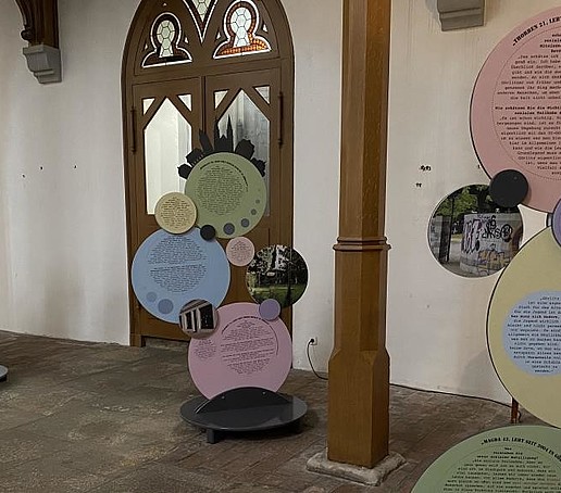 Round cut-out exhibits can be seen in a church. A church door in the background.